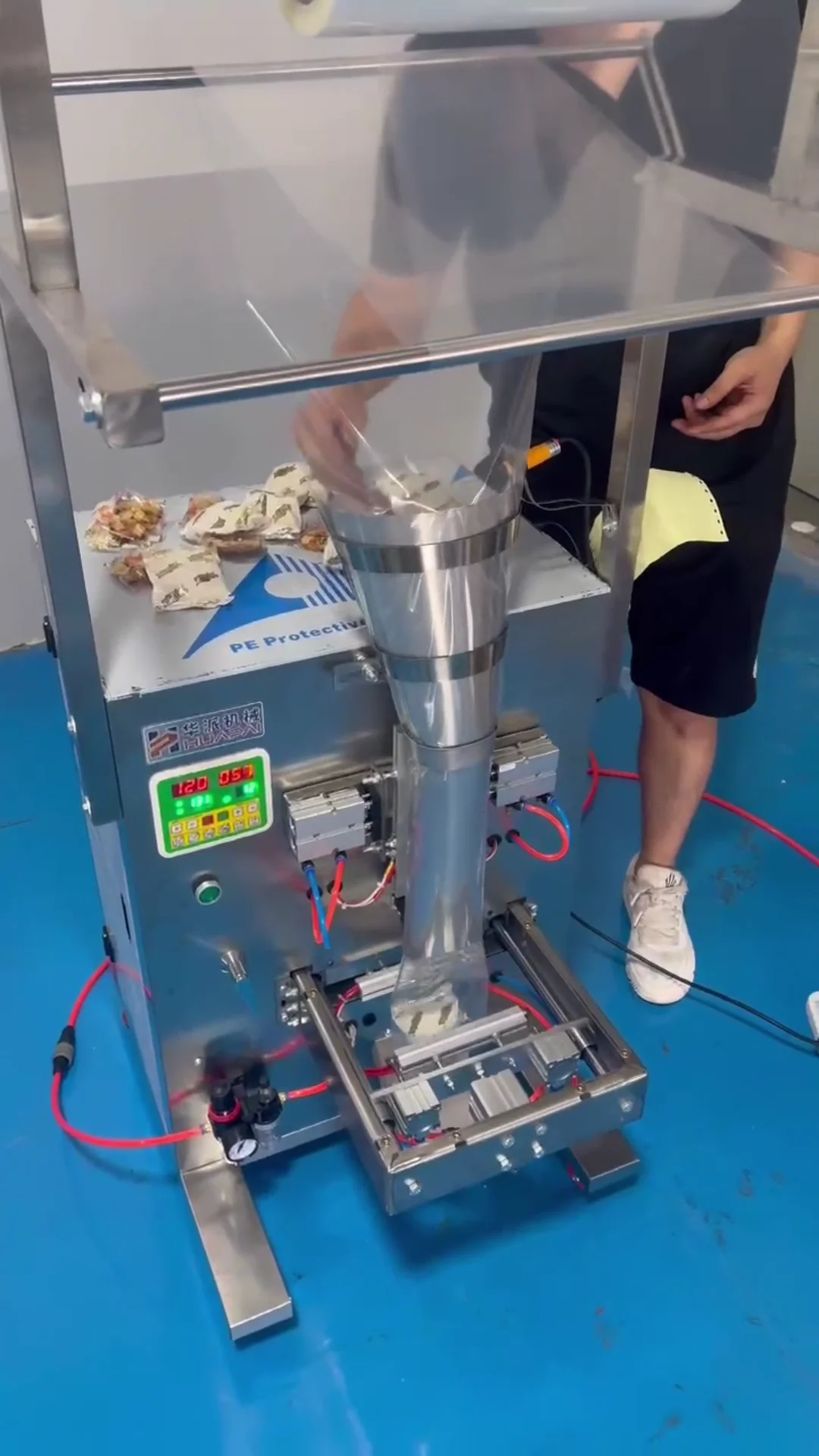 Semi-automatic manual drop-feeding vertical form fill seal packaging machine with sealed pouches in modern manufacturing facility